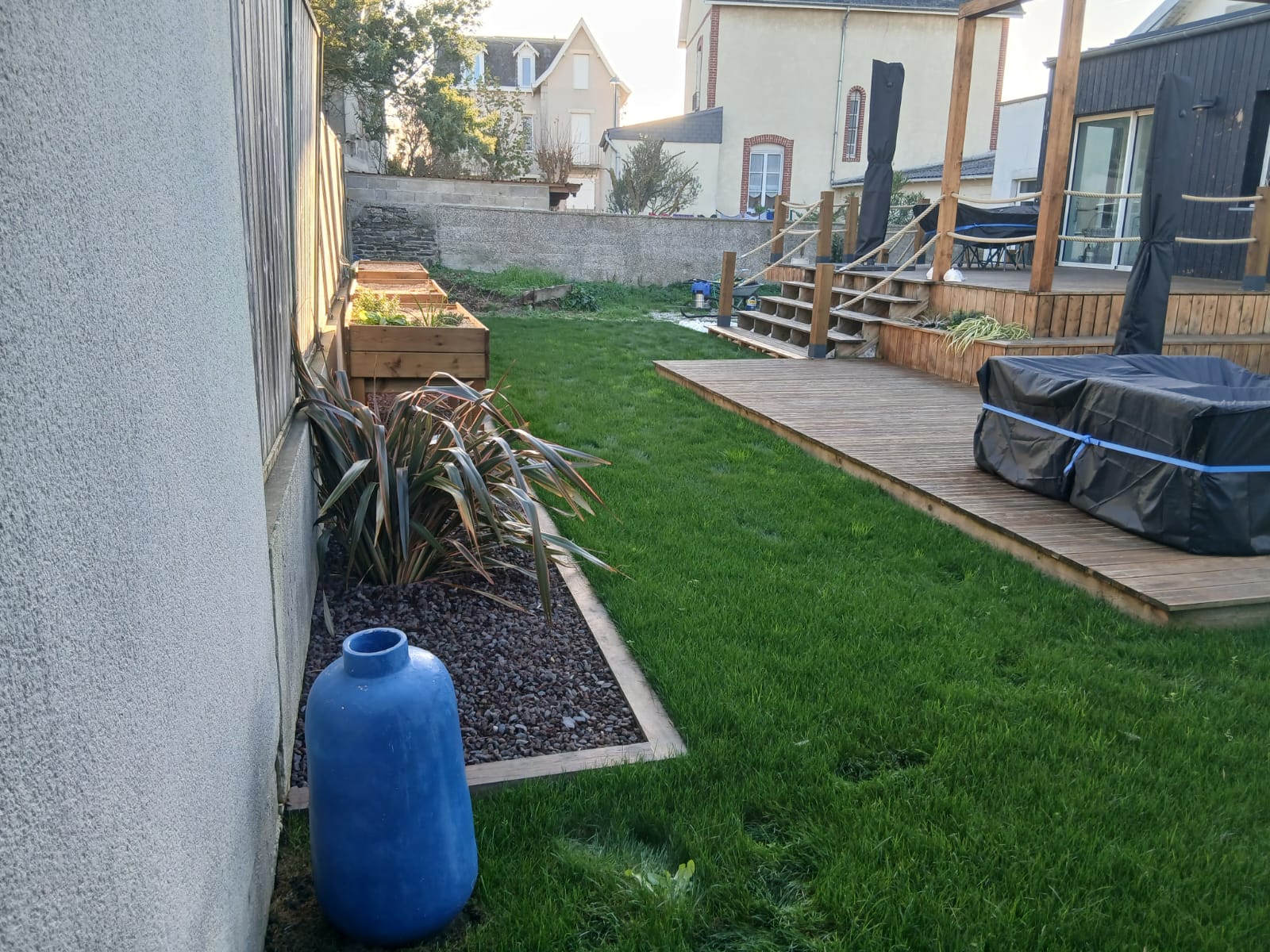 Jardin aménagé avec pelouse, massifs et terrasse en bois par Les Jardins du Val de Vire